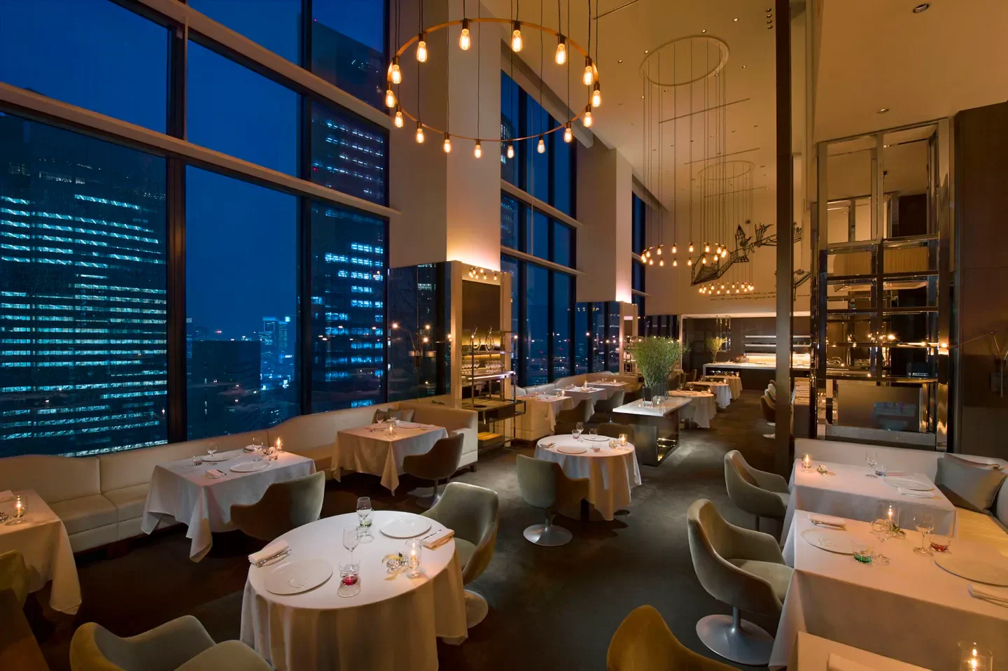 Elegant dining room at Collage restaurant in Tokyo with city view at night.