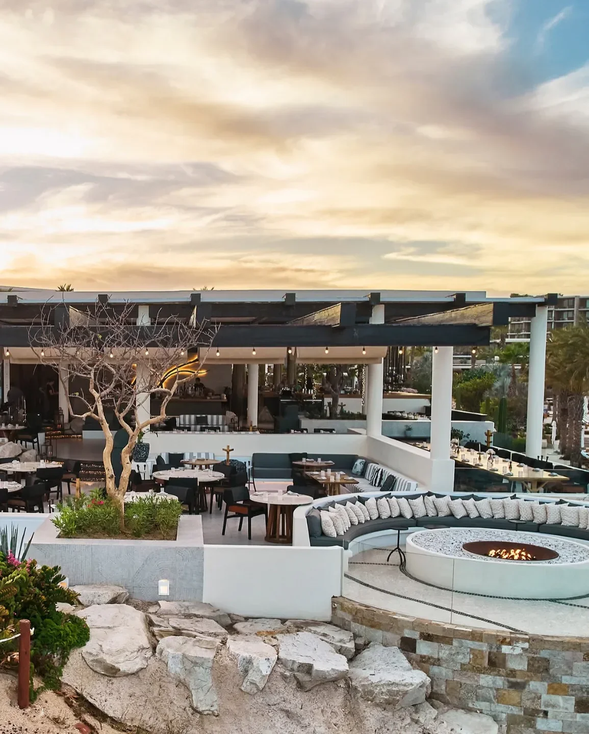 Outdoor seating at Comal restaurant in Los Cabos with a fire pit at sunset.