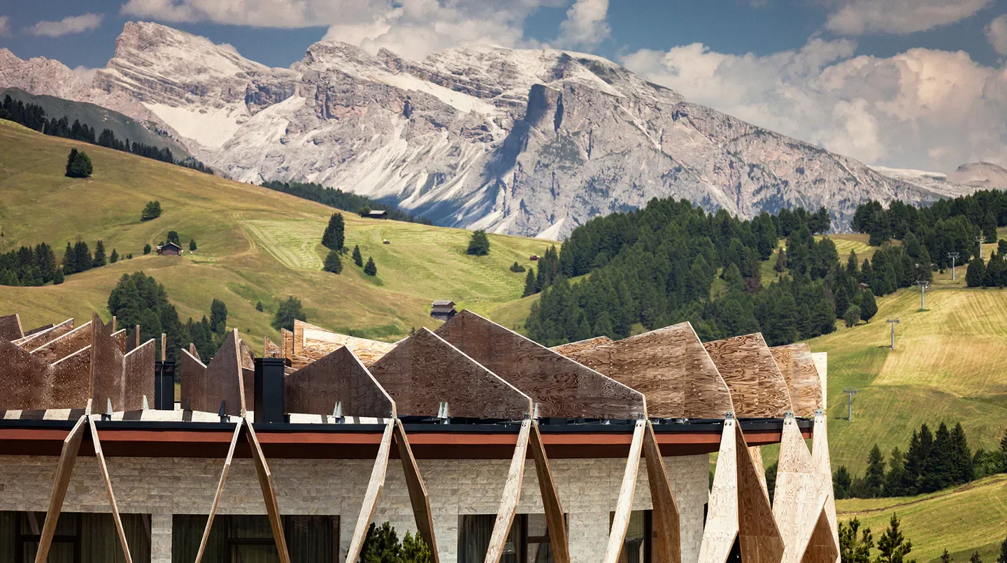 Exterior view of the COMO Alpina Dolomites hotel in Taormina, with mountain backdrop.
