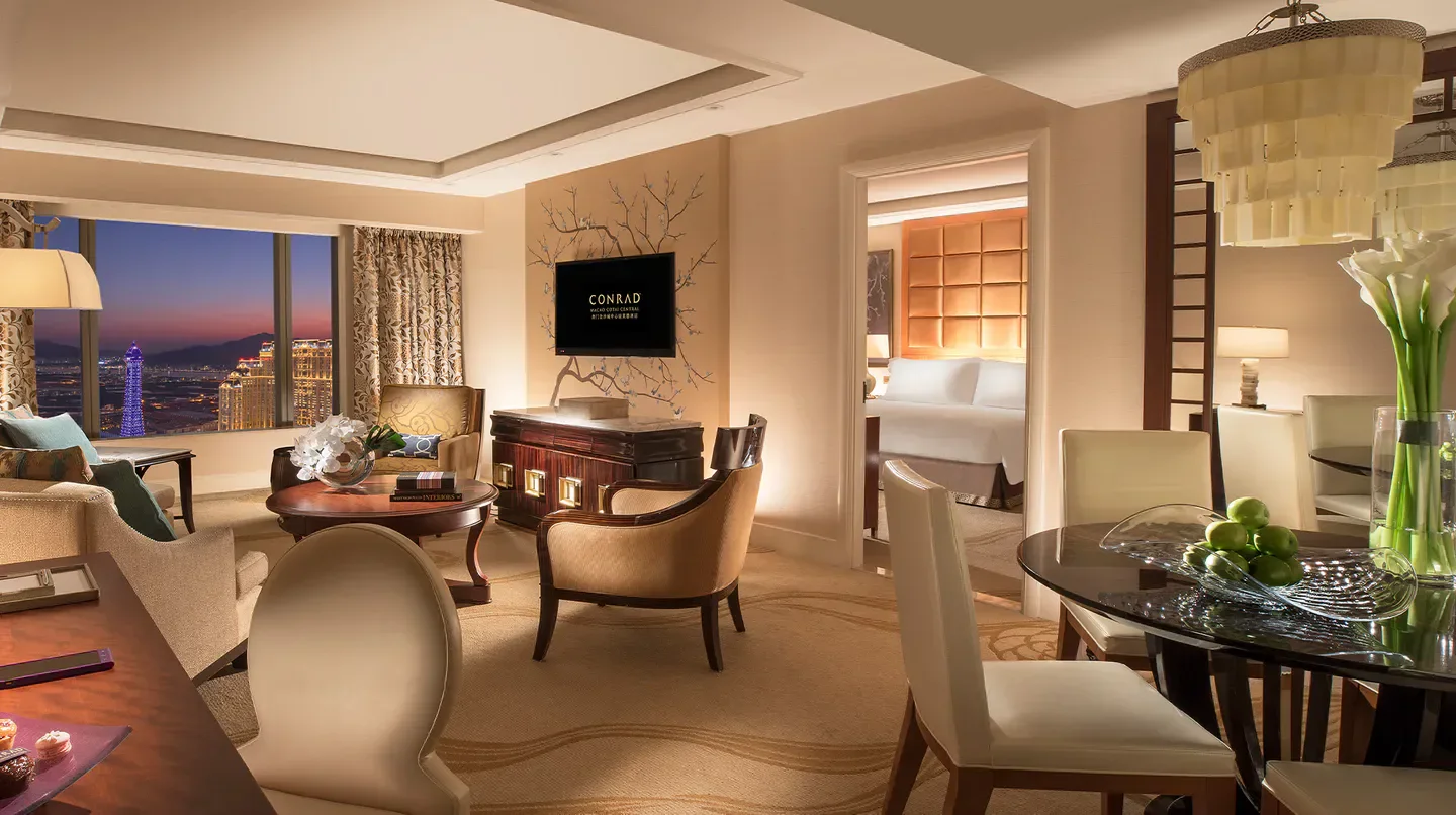 Elegant suite at Conrad Macao hotel, with a stunning Macau city view at dusk.