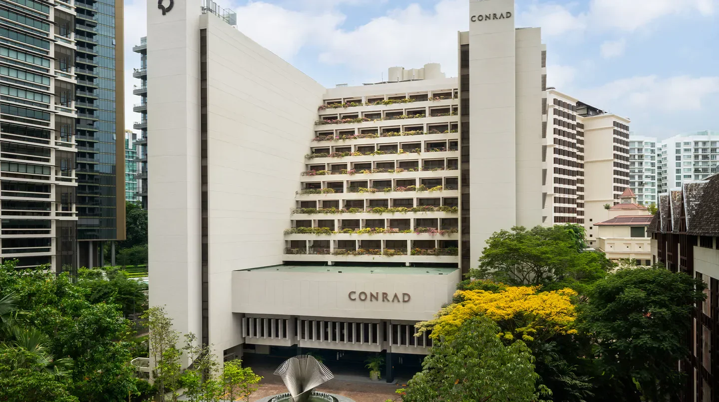 Exterior view of Conrad Singapore Orchard hotel in Singapore, with greenery.