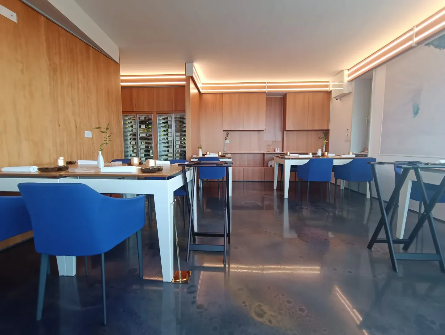Interior view of Contaminazioni Restaurant in Campania, featuring blue chairs and wooden accents.