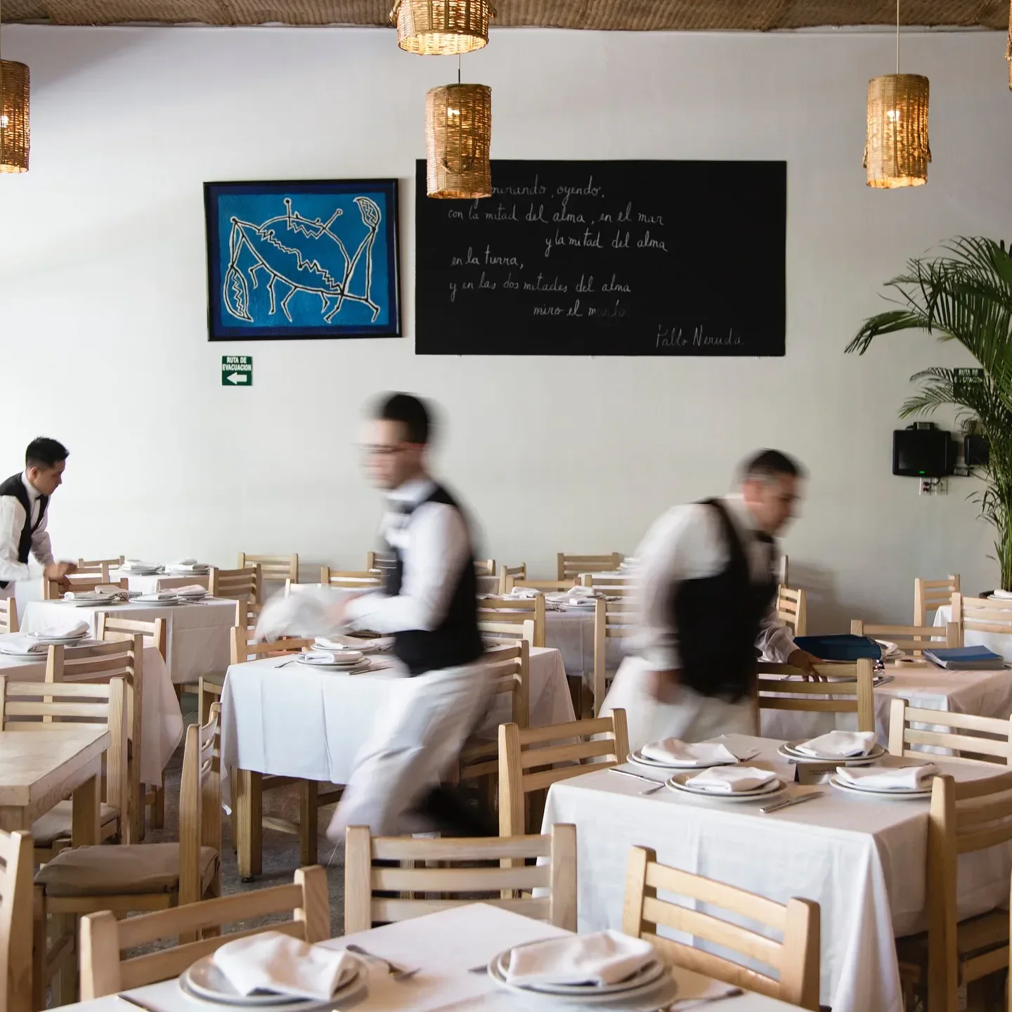 Dining room at Contramar restaurant in Mexico City, with waiters preparing tables.