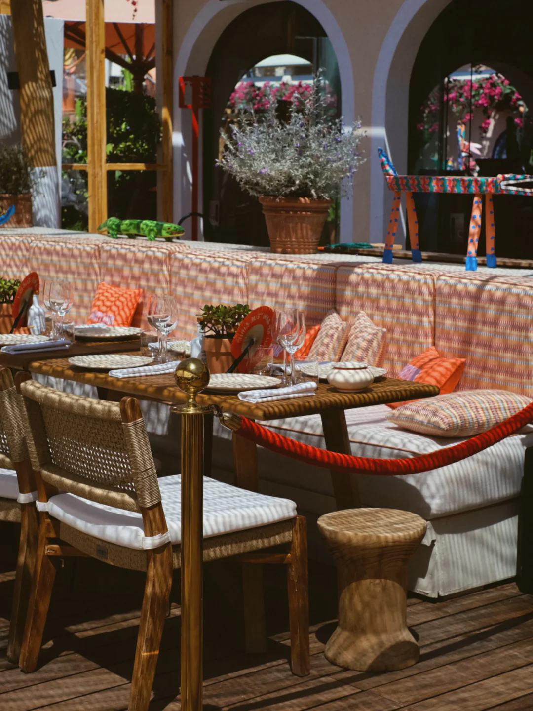 Bohemian outdoor dining setup at Copal Beach restaurant in Cannes with colorful cushions and woven chairs.