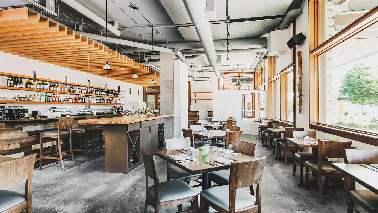 Interior of Copine restaurant in Seattle with wood details and a bar.