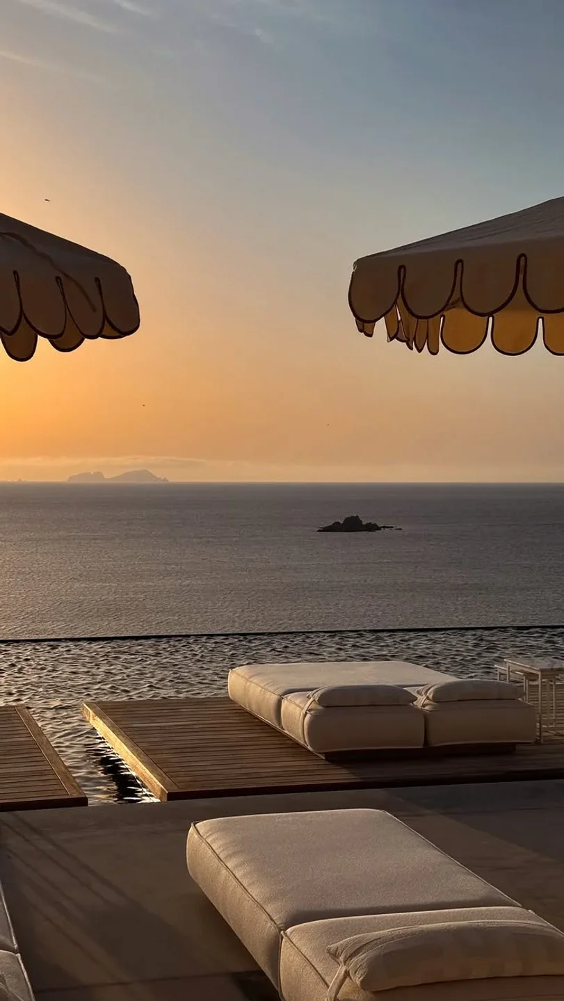 Relaxing daybeds by the infinity pool at Corbu Mykonos with stunning sunset ocean views.