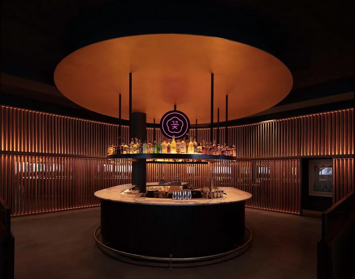 Stylish bar at COTE Miami with illuminated wood paneling and a large circular canopy
