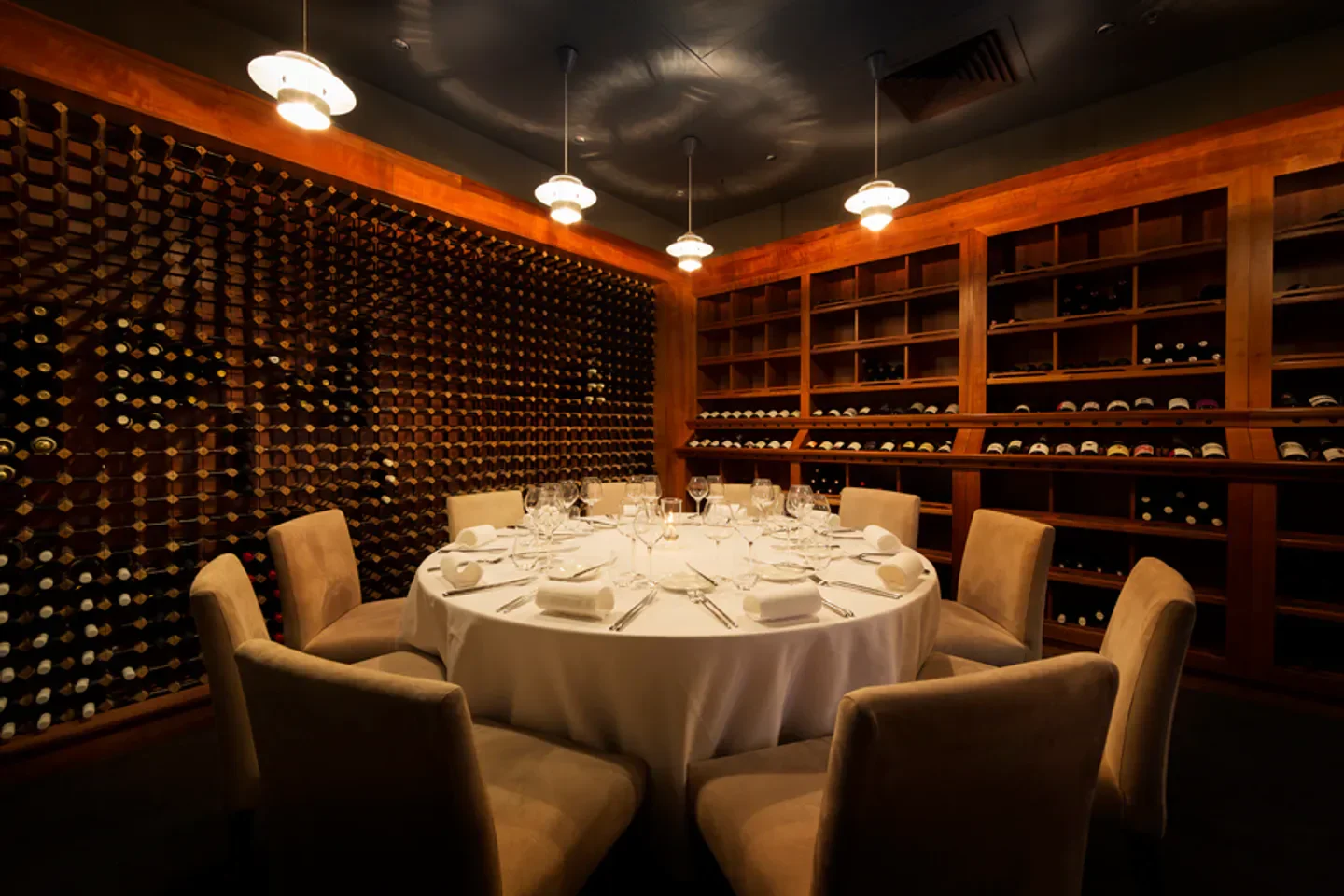 Elegant dining room at Courgette restaurant in Canberra, showcasing wine collection and fine dining setup
