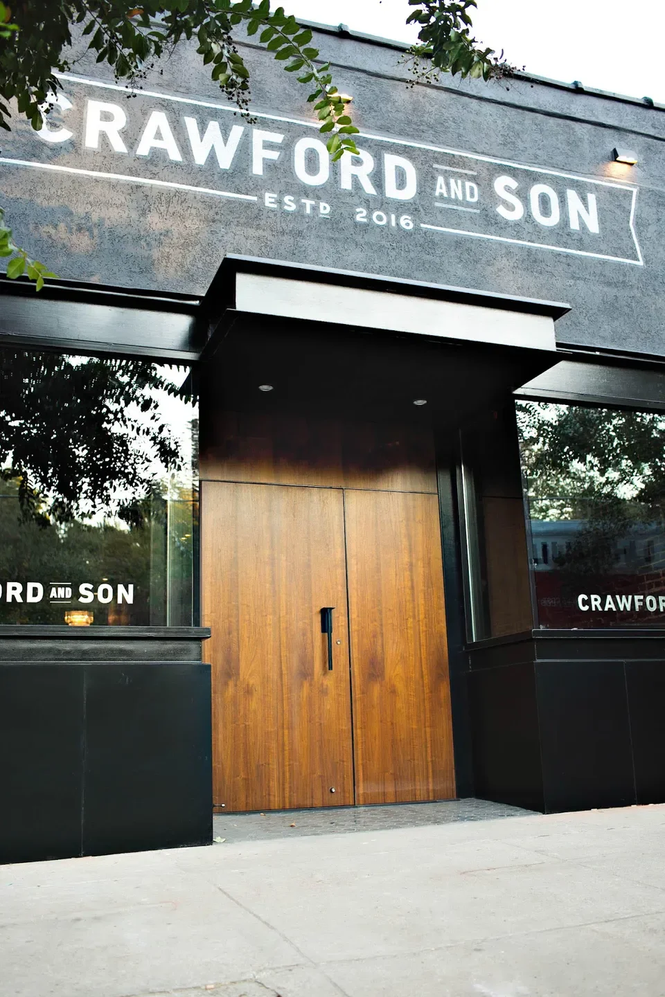 Exterior of Crawford & Son restaurant in Raleigh, featuring wooden door and signage.