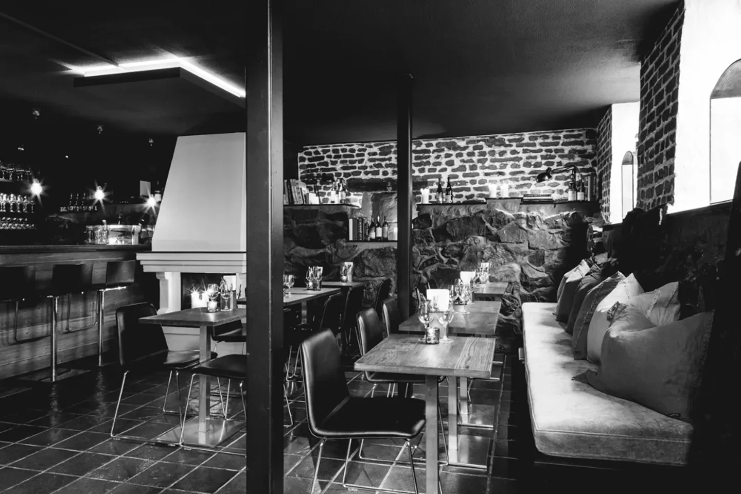 Cozy interior of Cru in Oslo, Norway, with stone walls and intimate dining setting.