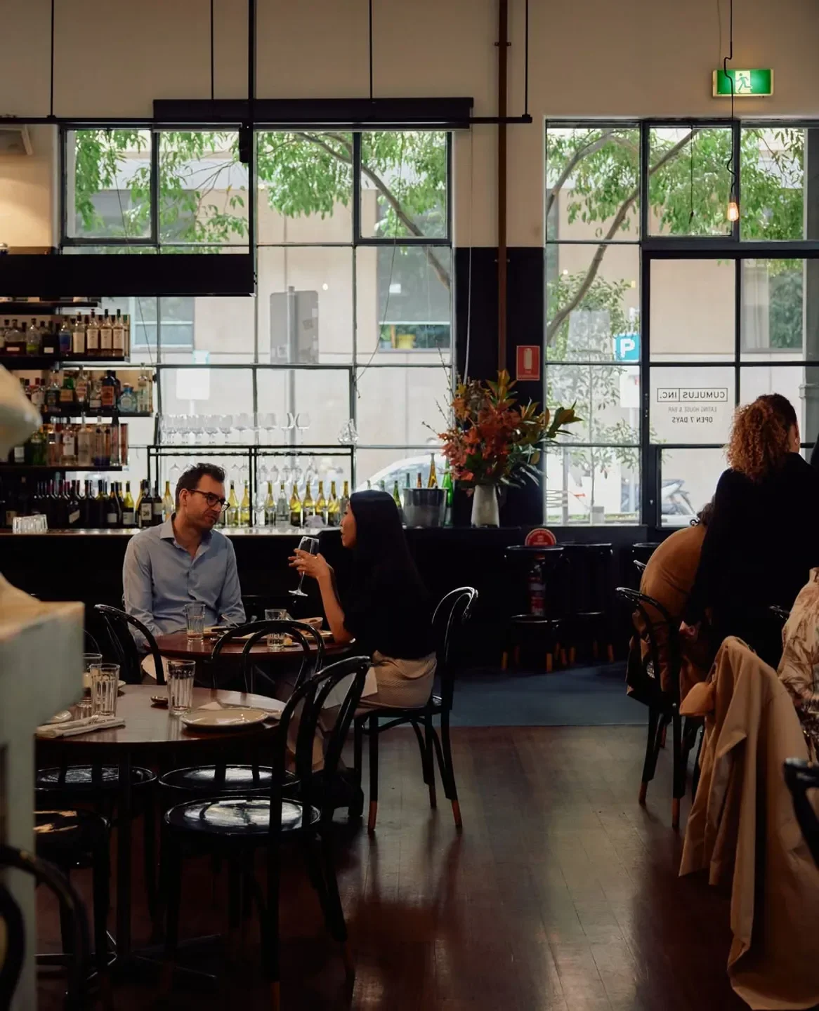 Dining at Cumulus Inc. restaurant in Melbourne, with natural light and bar in background.