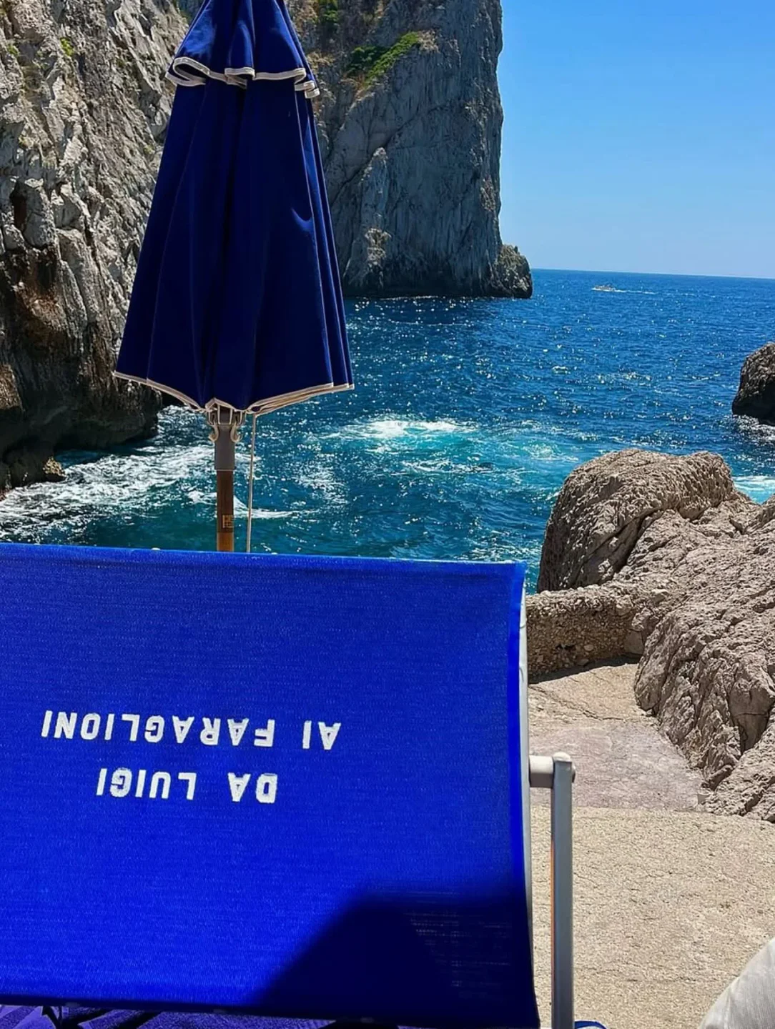 Da Luigi ai Faraglioni beach club in Capri with azure waters and rocky coastline.