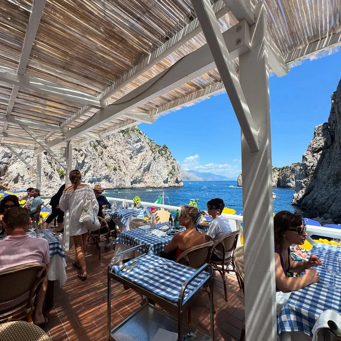 Terrace dining at Da Luigi ai Faraglioni in Capri with stunning views of the Faraglioni rocks and blue sea.
