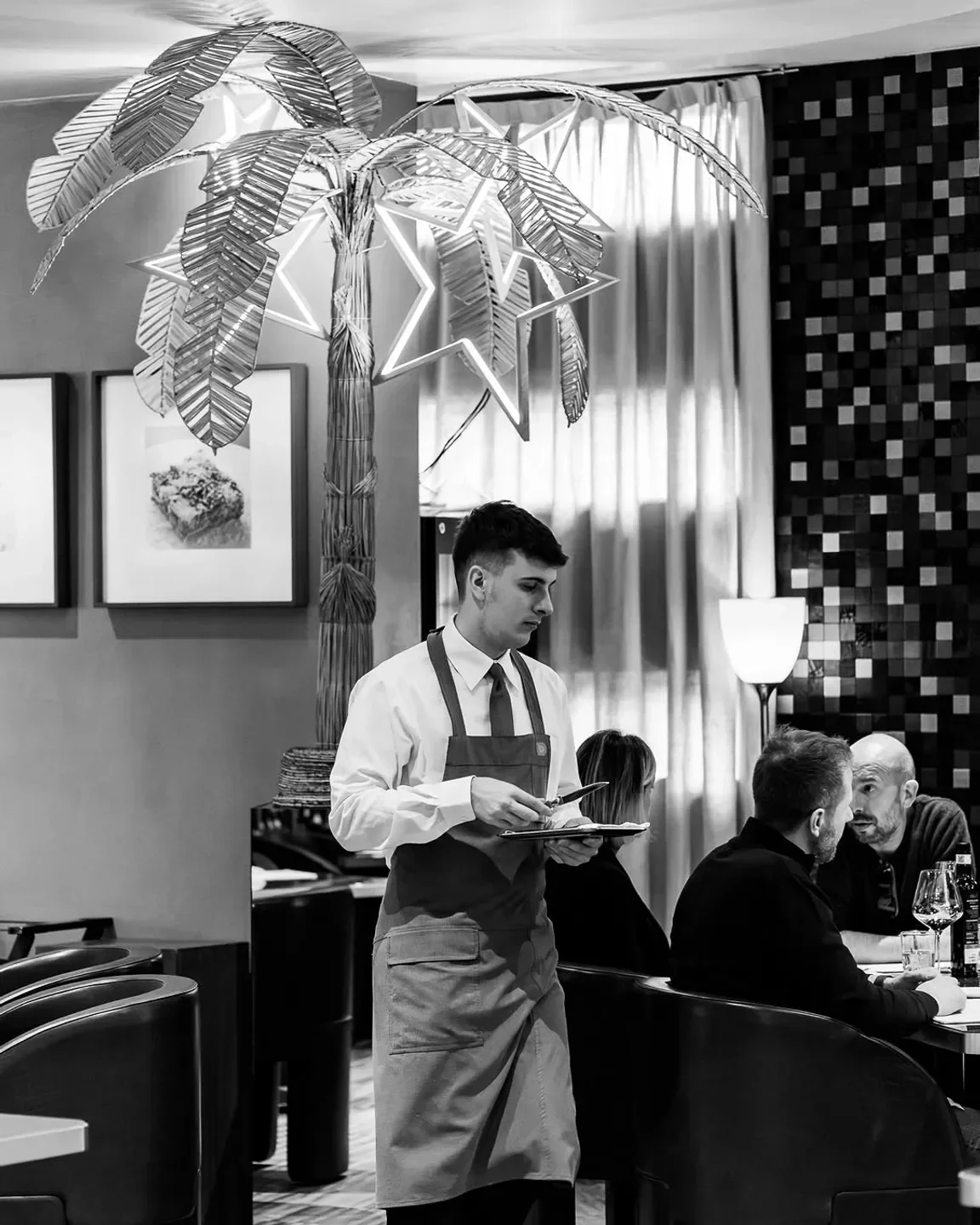 Waiter at Damini Macelleria & Affini in Veneto serving customers in a stylish restaurant