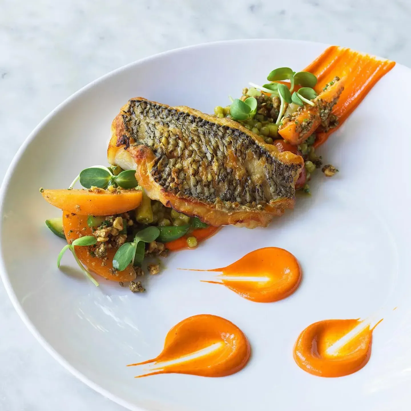 Delectable fish dish from Deuxave in Boston, artfully plated with vibrant sauces.