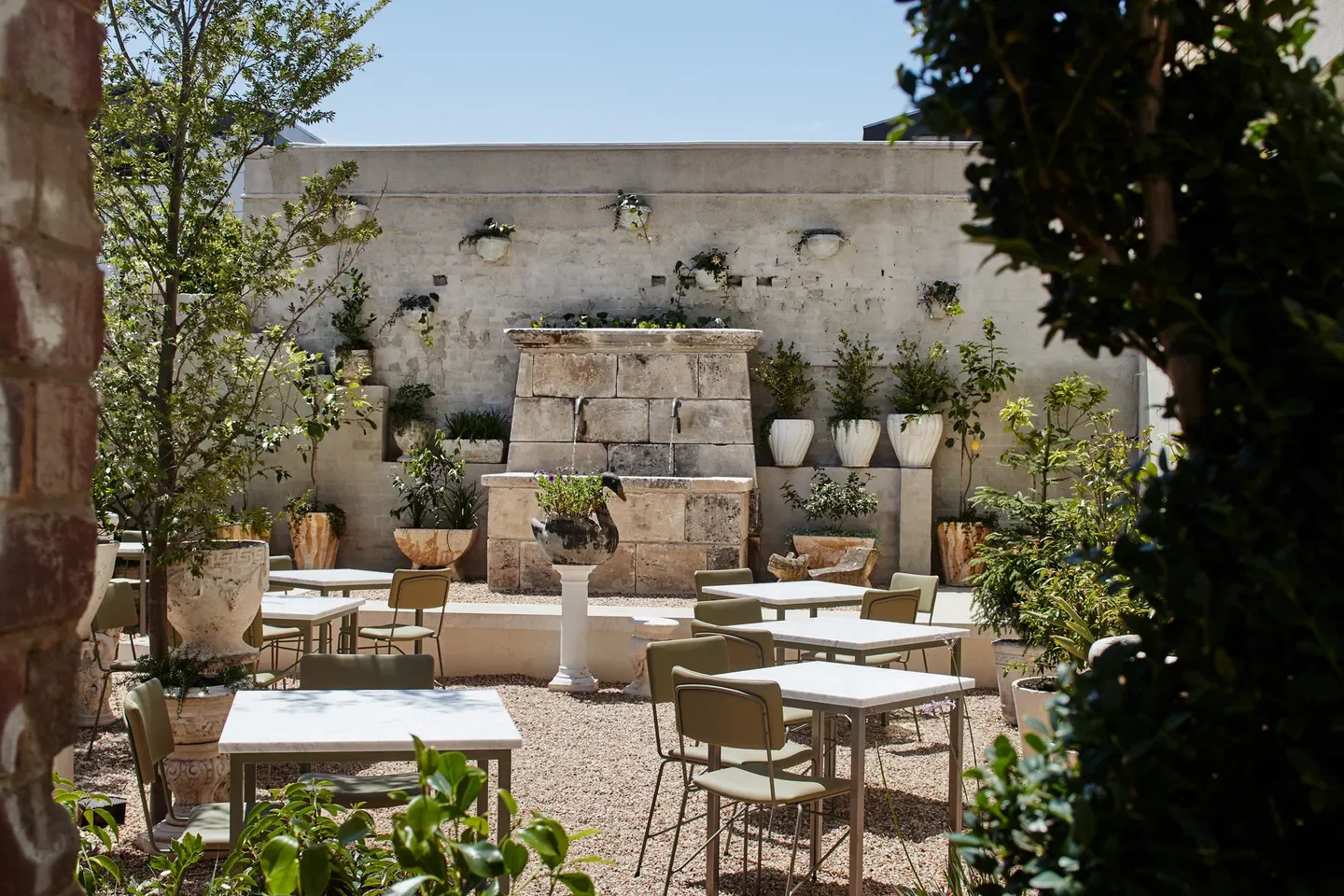 Outdoor dining area at Di Stasio Carlton in Melbourne, with tables and a stone water feature.