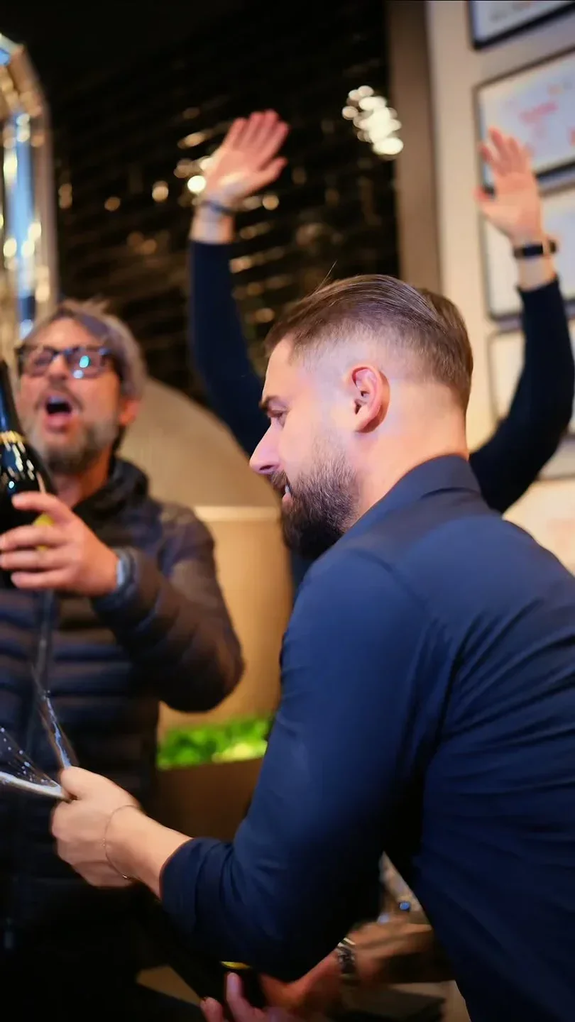 Celebration at Diego Vitagliano Pizzeria in Napoli with champagne, raising hands in joy.