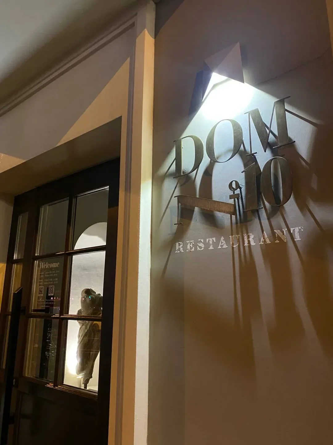 Exterior view of Dom No. 10 restaurant in Kyiv at night, illuminated signage and entrance.