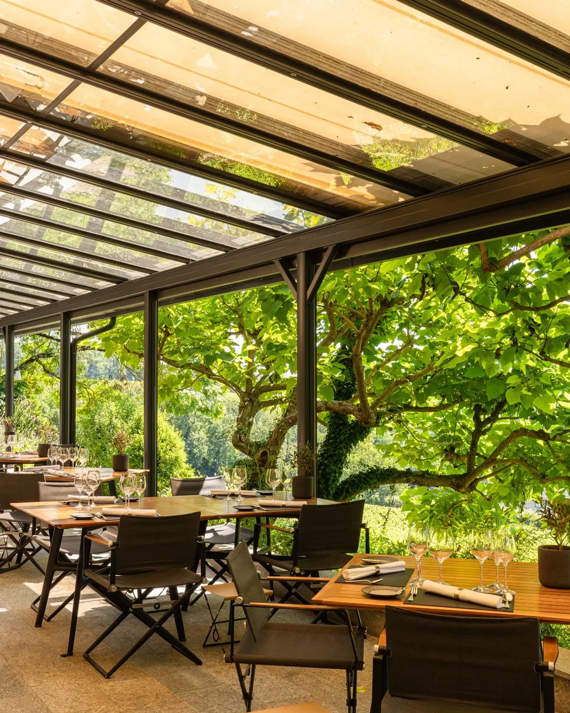 Outdoor dining area at Domaine de Châteauvieux in Geneva, Switzerland, featuring tables set for service with a beautiful garden view.