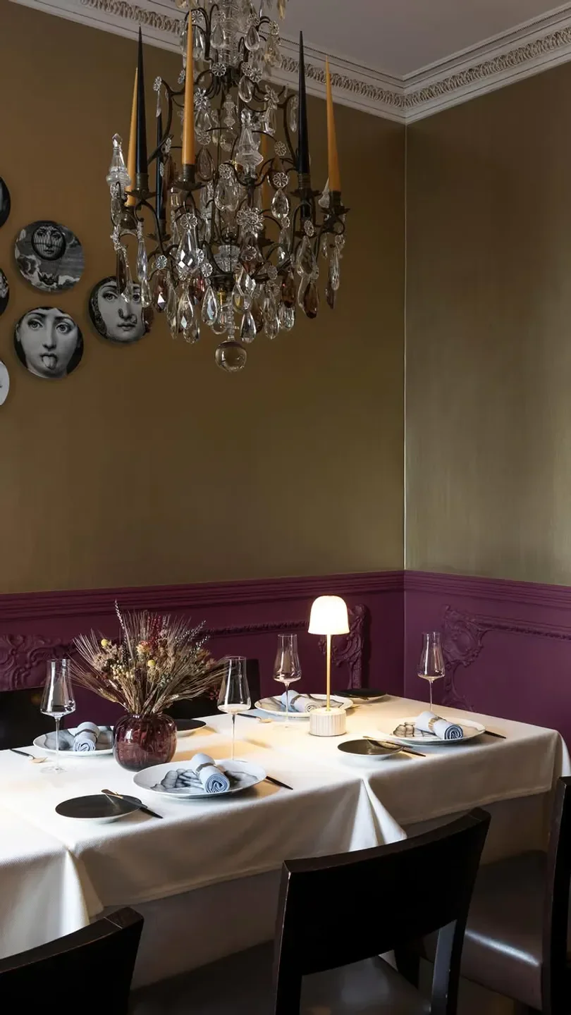 Elegant dining at Dôme restaurant in Antwerp: Chandelier and decorated plates on the wall.