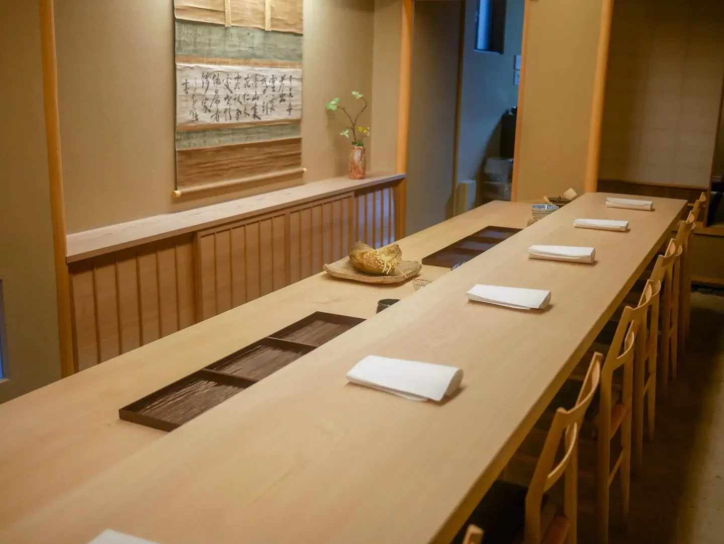 Interior of Doujin restaurant in Kyoto, featuring a long wooden table and minimalist design.