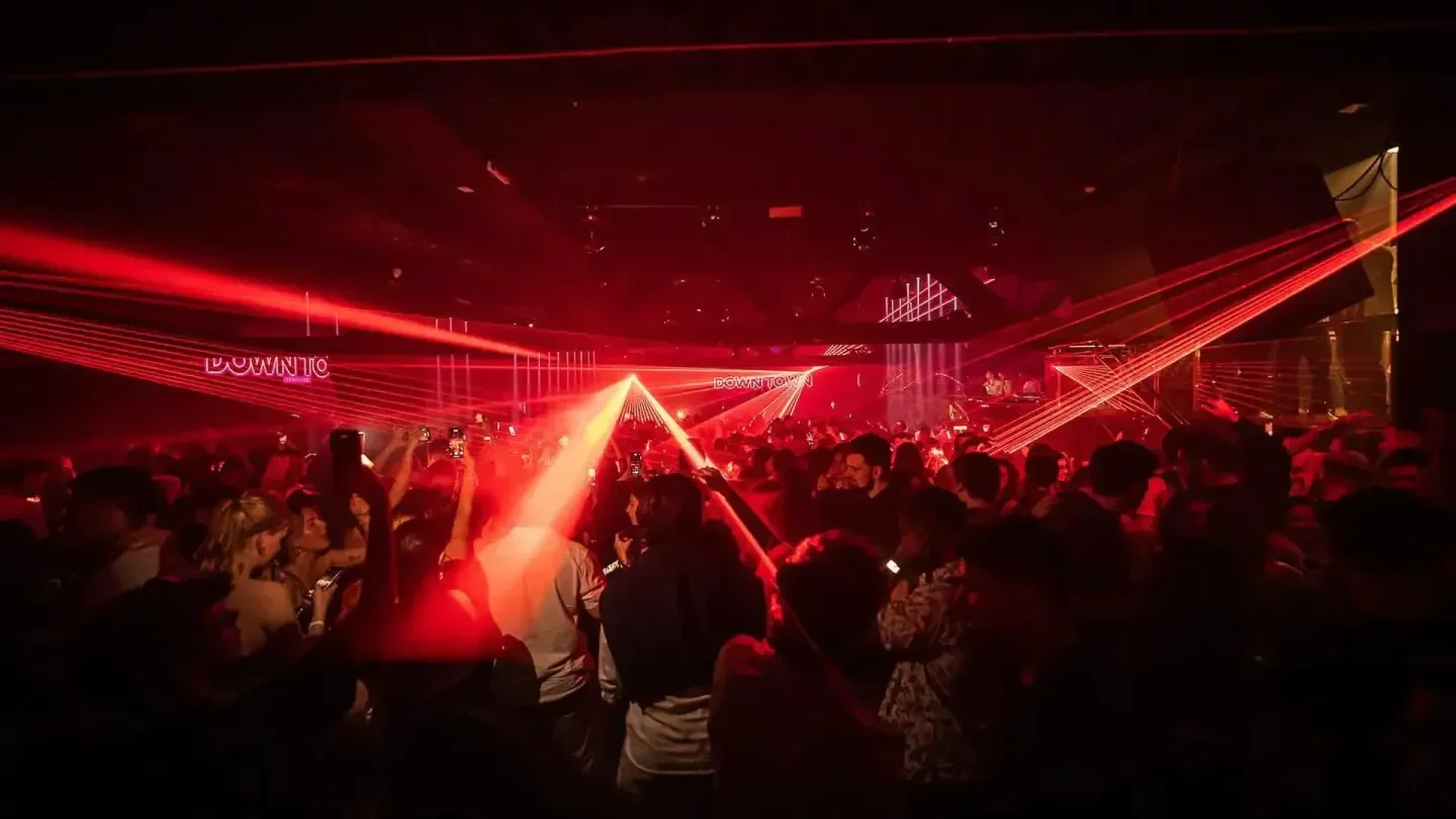 Energetic night at Downtown Barcelona nightclub, with red laser lights and crowd.