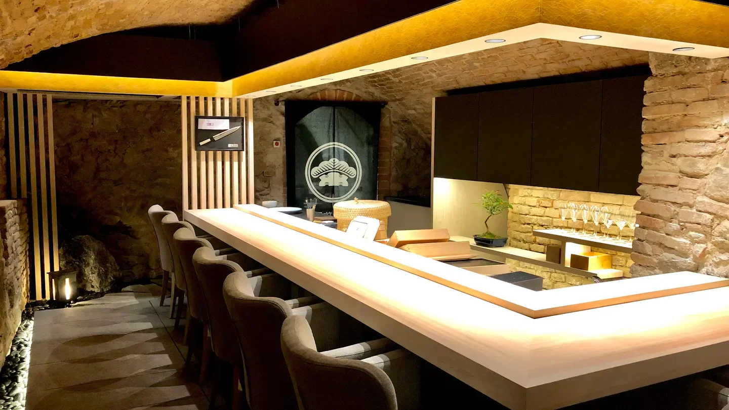 Elegant interior of Edomae Sushi Matsuki in Bratislava, with sushi bar and stone walls.