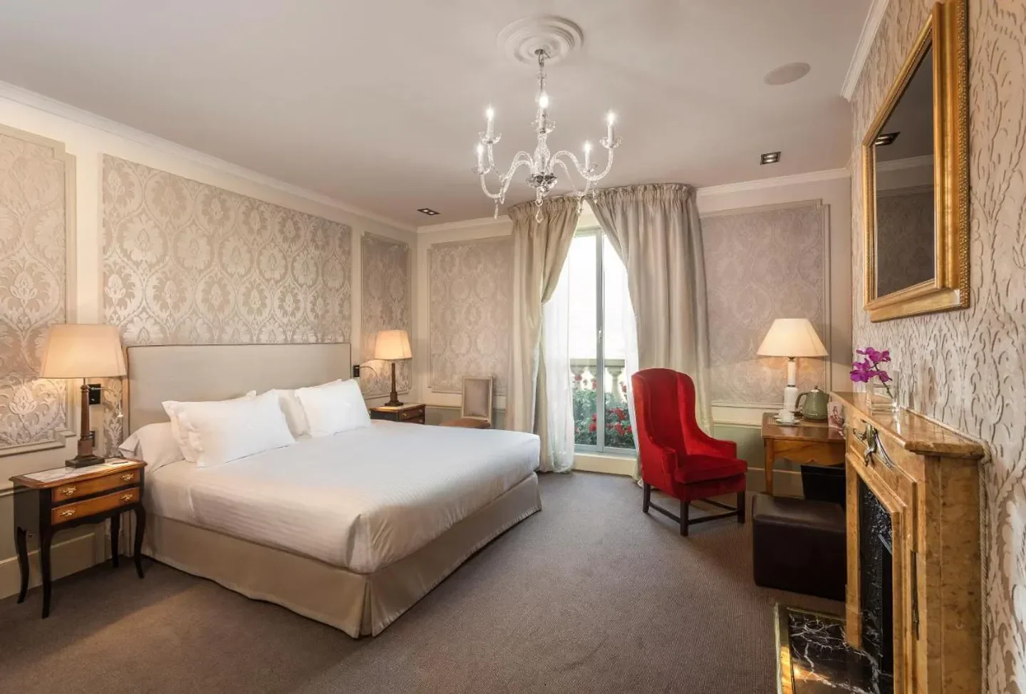 Elegant bedroom at El Palace Barcelona hotel. Luxury decor in Barcelona, featuring chandelier and fireplace.