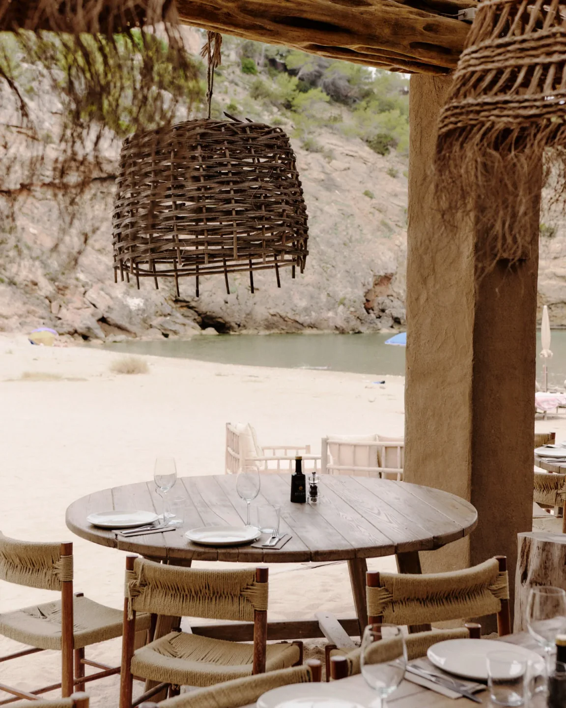 El Silencio Ibiza restaurant with rustic wooden tables and chairs set on a sandy beach.