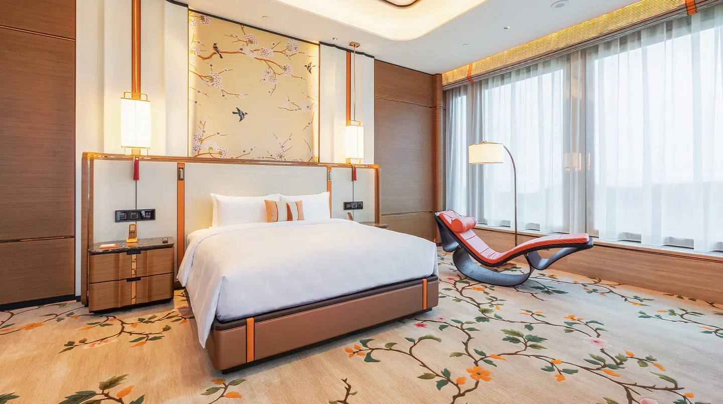 Elegant bedroom at Emerald Tower at MGM COTAI in Macau, featuring floral carpet and art.