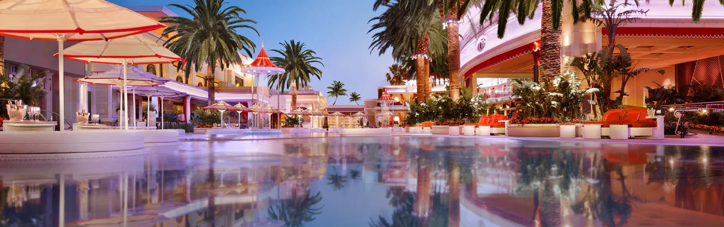 Encore Beach Club at Night in Las Vegas features elegant poolside seating, palm trees, and vibrant lighting reflecting in the water.