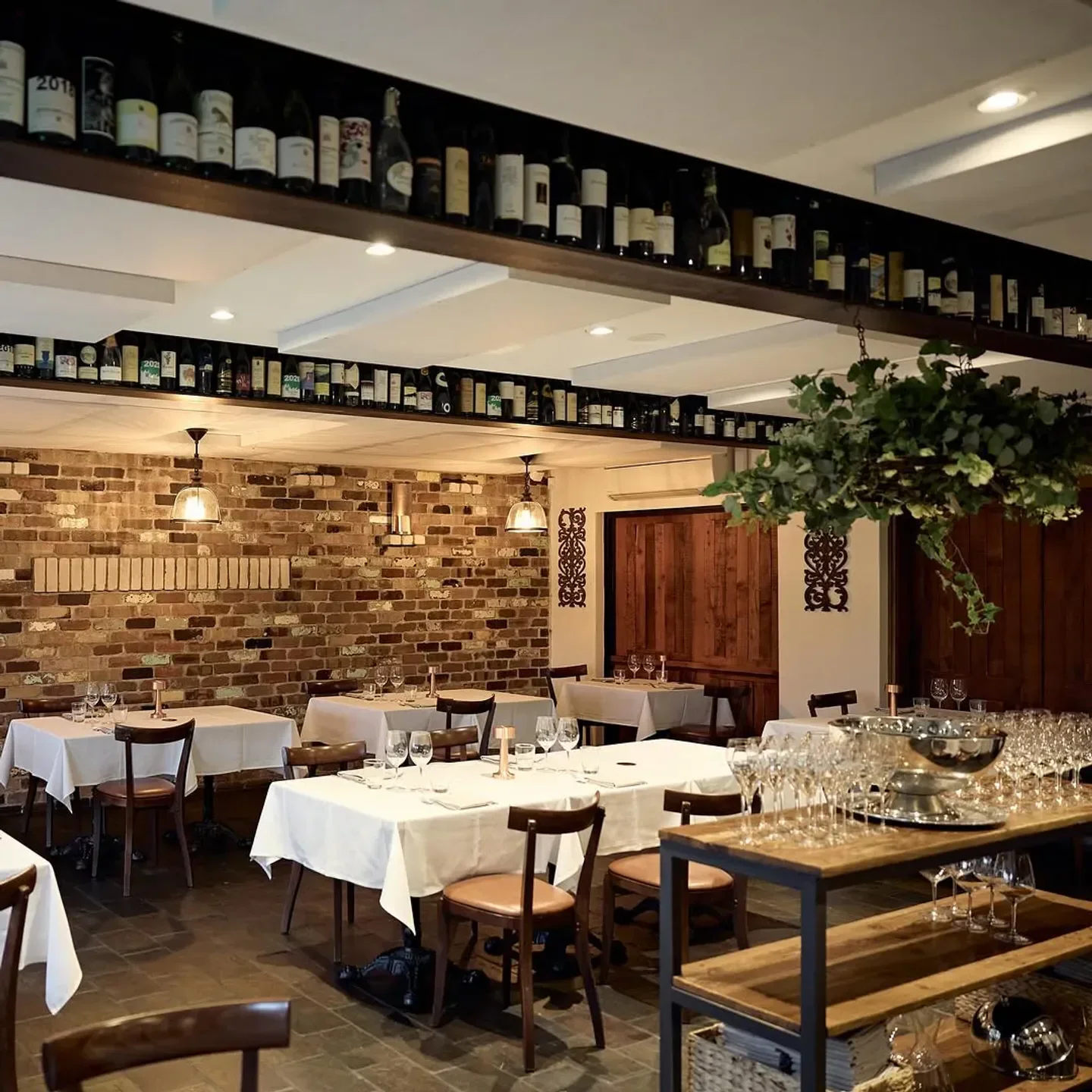 Interior of Entrata restaurant in Sydney, featuring tables, wine bottles, and rustic brick wall.