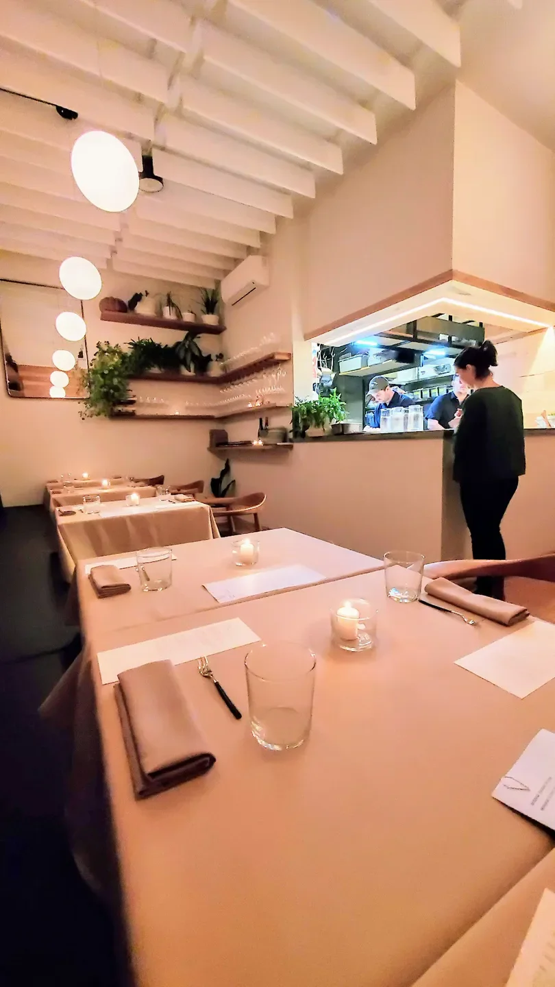 Cozy interior of Erizo restaurant in Portland, with tables set and open kitchen view.