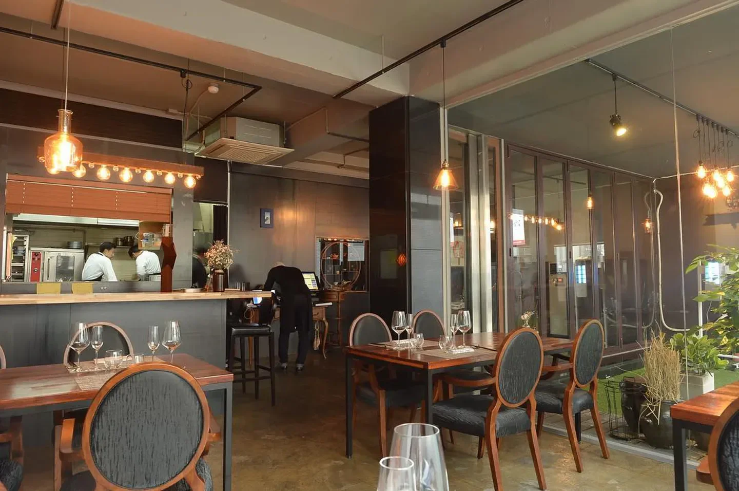Interior of Exquisine restaurant in Seoul, featuring dining tables and open kitchen area.