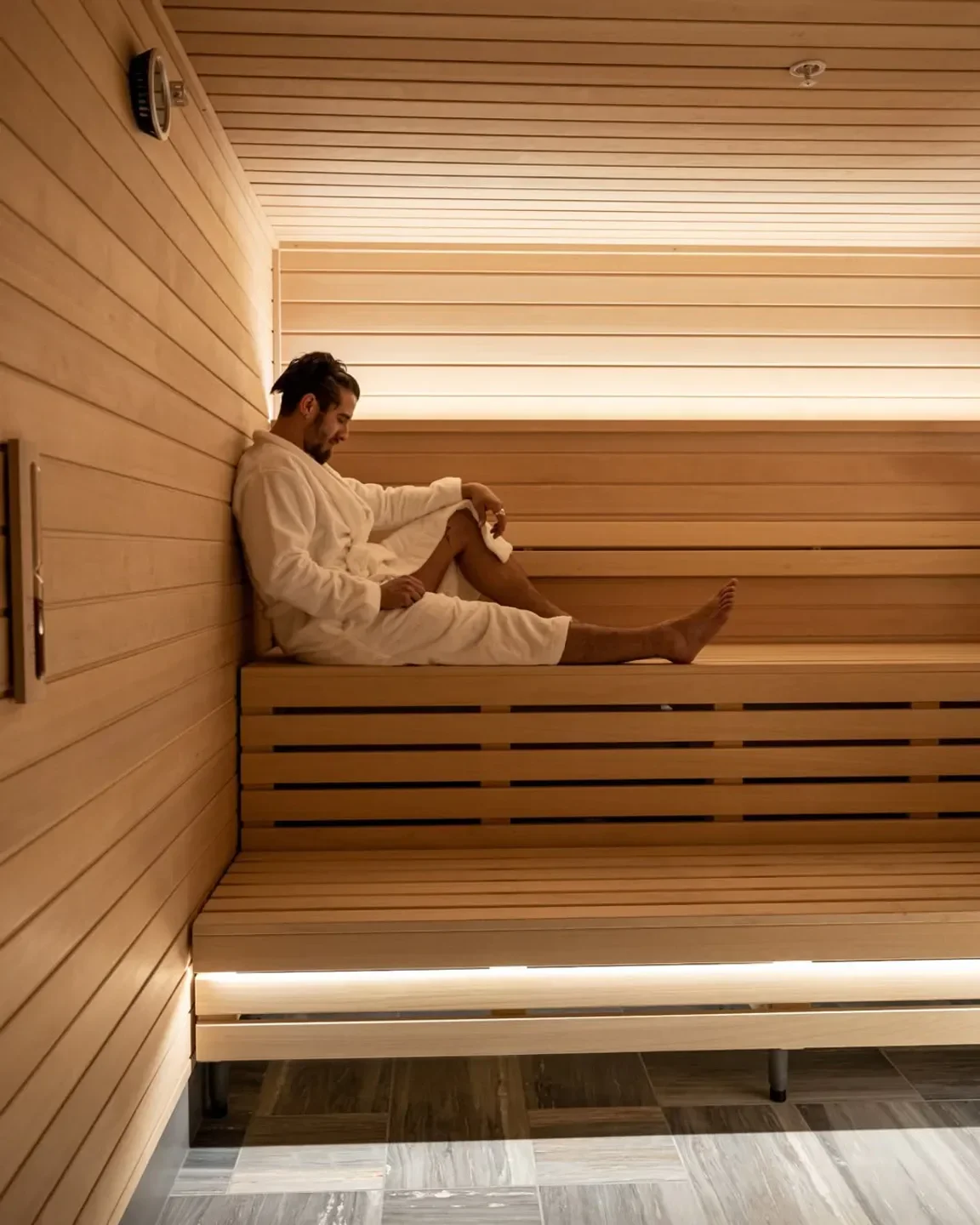 Man relaxing in sauna at Fairmont Spa Century Plaza, Los Angeles, wearing a robe.