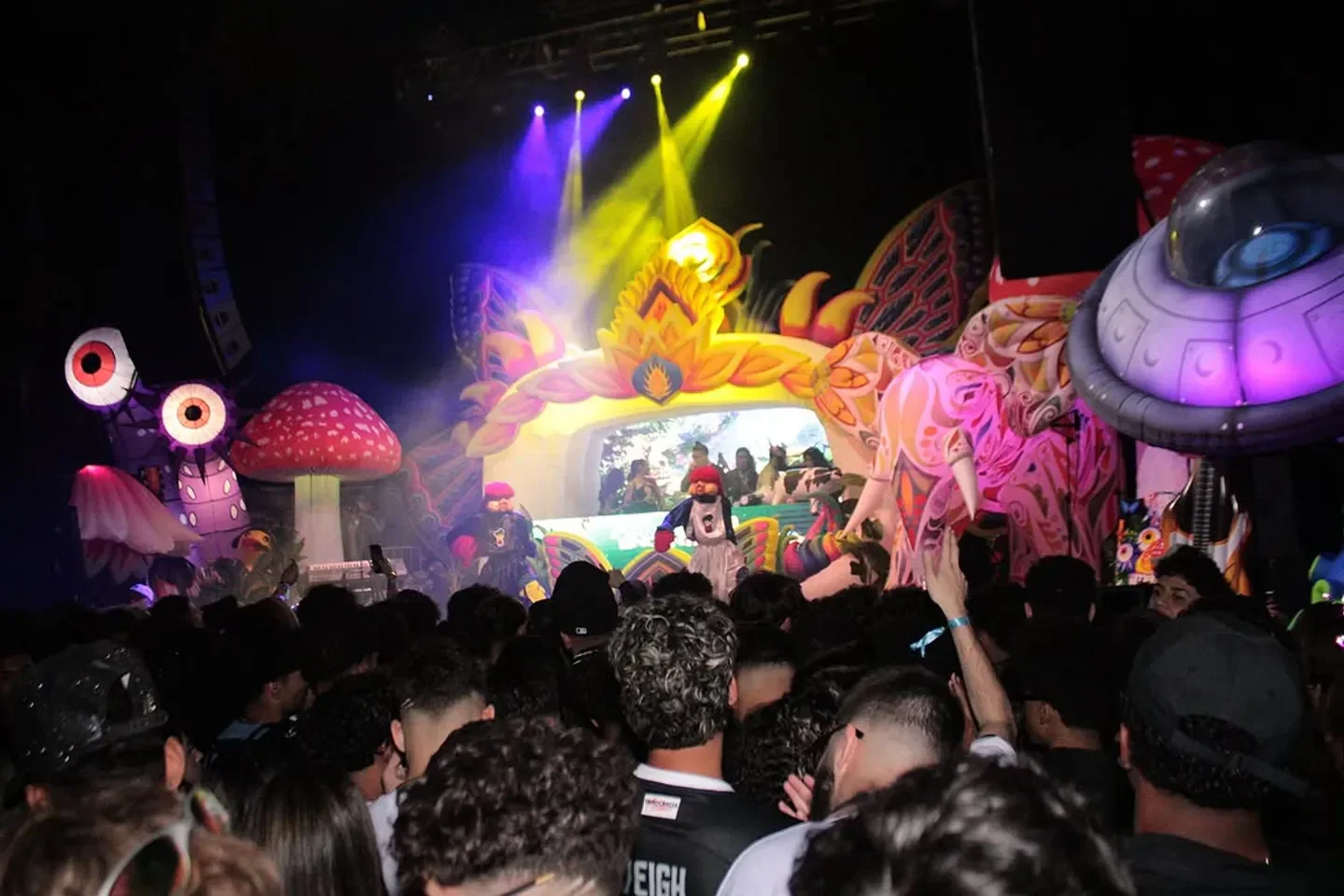 Colorful crowd at Favela Encantada nightclub in Boston enjoying a vibrant party with stage decor.