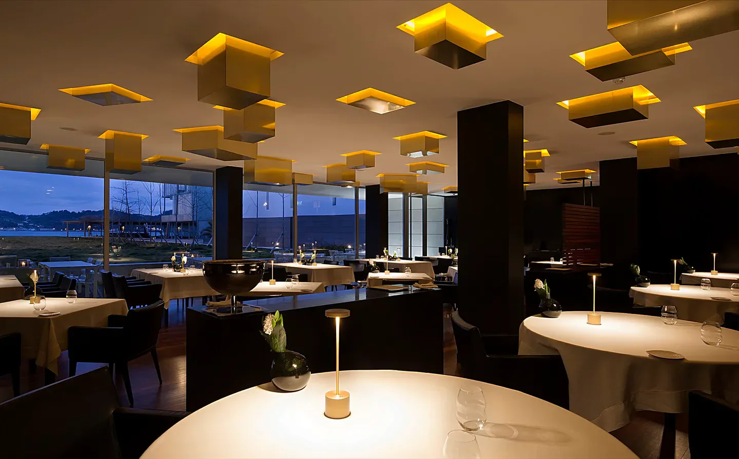 Elegant dining room at Feitoria, Lisbon, with modern lighting and waterfront views.