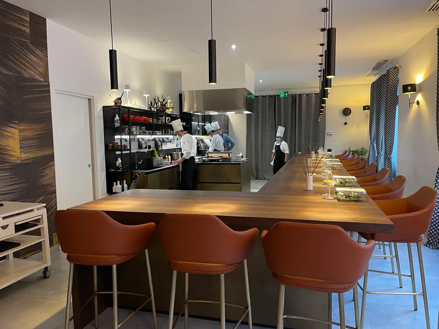 Chefs preparing food at Felix Lo Basso home & restaurant in Milan, with bar seating in view.