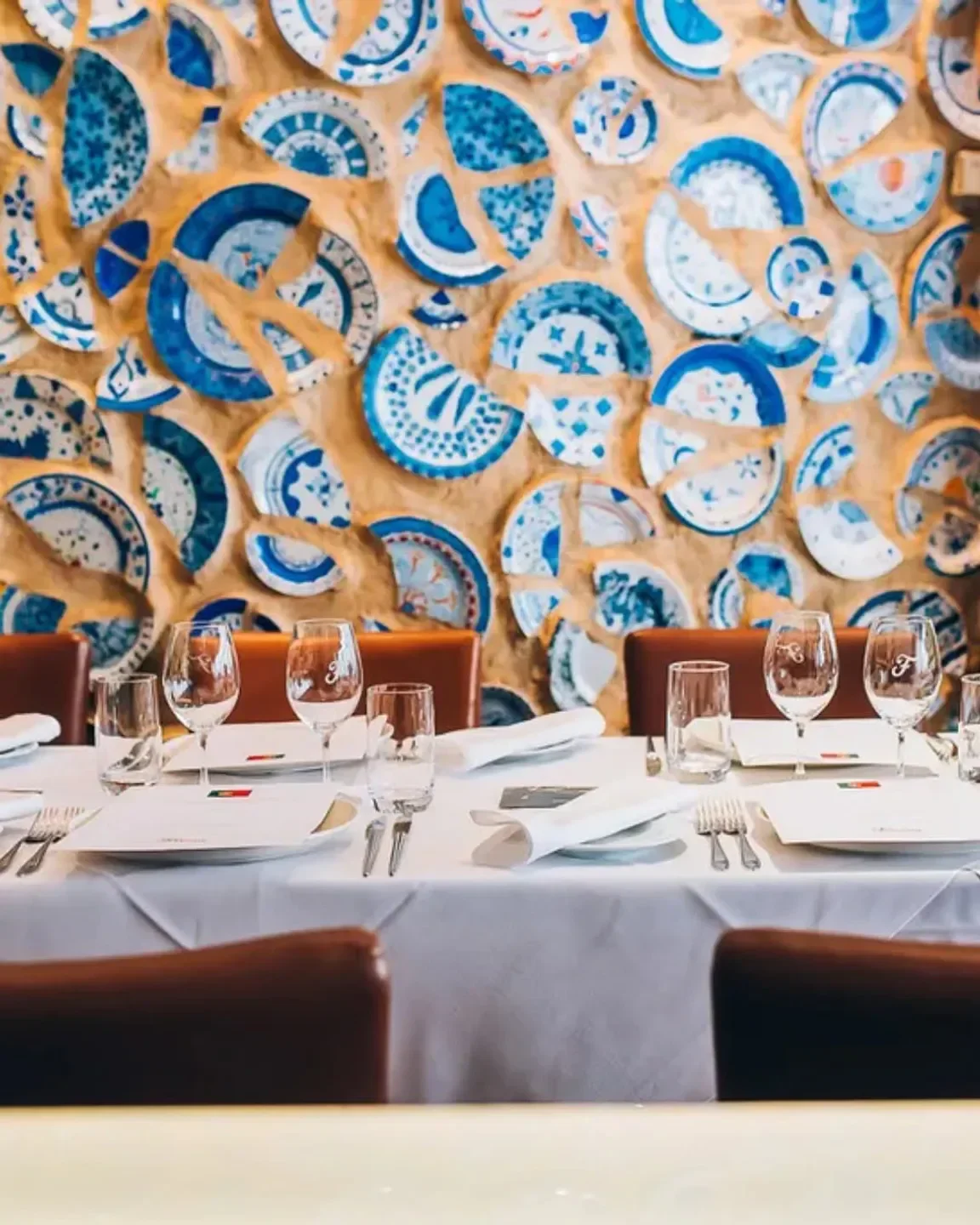 Interior of Ferreira Café in Montreal with artistic broken plate wall and table setting.