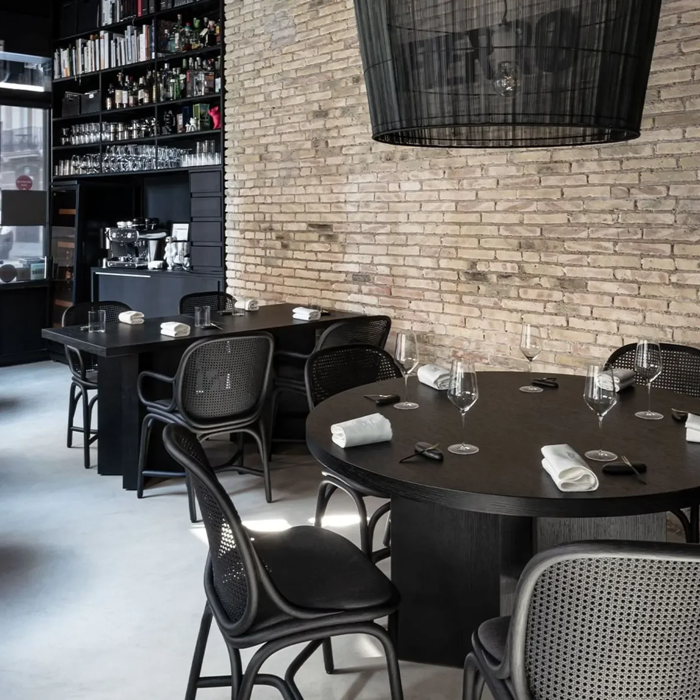 Interior of Fierro restaurant in Valencia with tables, chairs, and brick wall.
