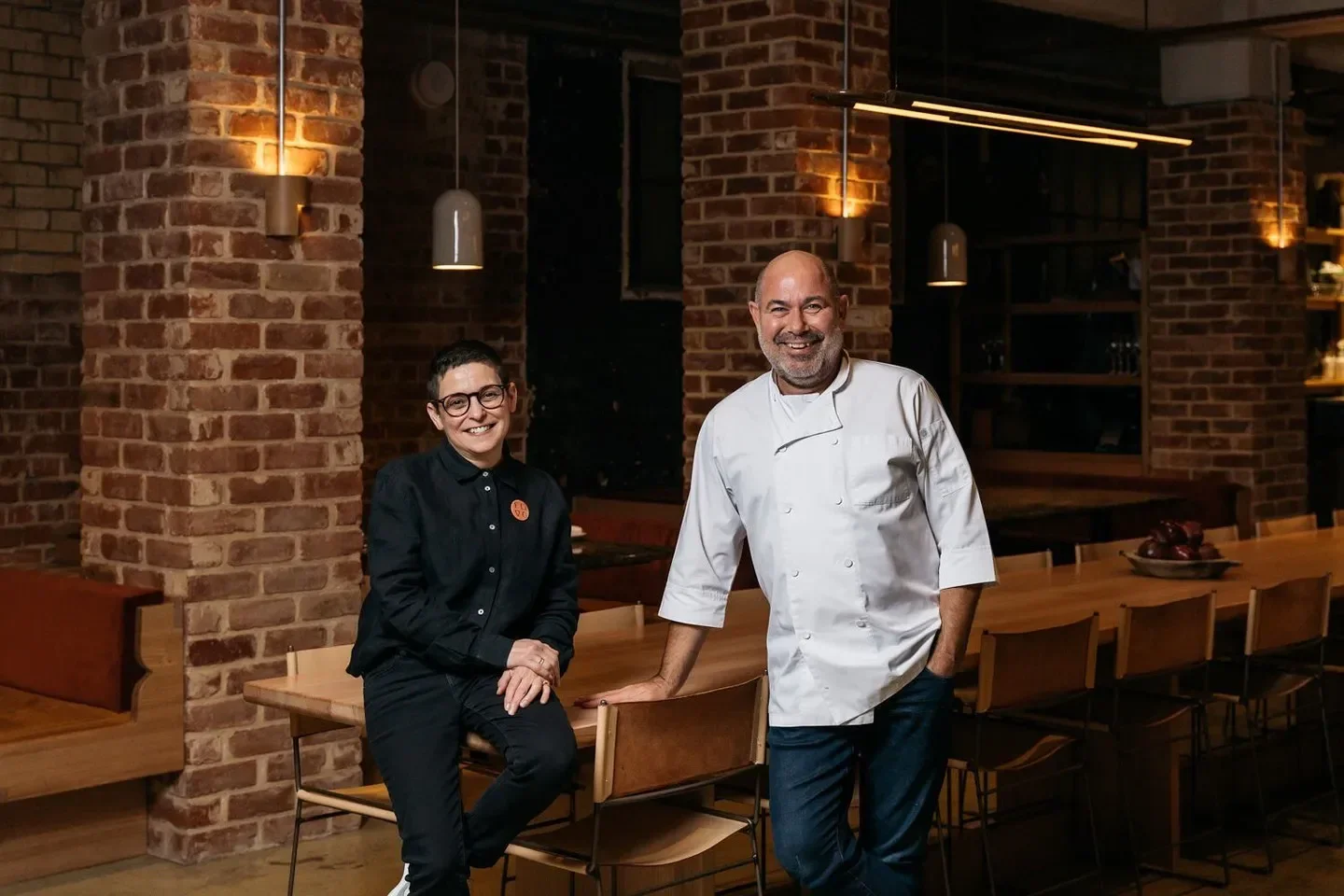 Chefs at Fino Vino Adelaide restaurant in front of a rustic brick wall and table.