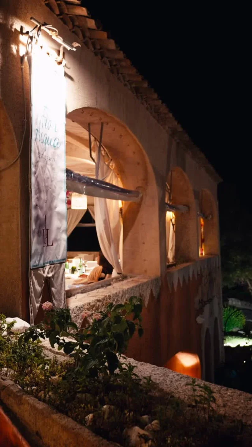 Fior d'Acqua restaurant exterior in Porto Cervo at night, showcasing arched windows and ambient lighting.