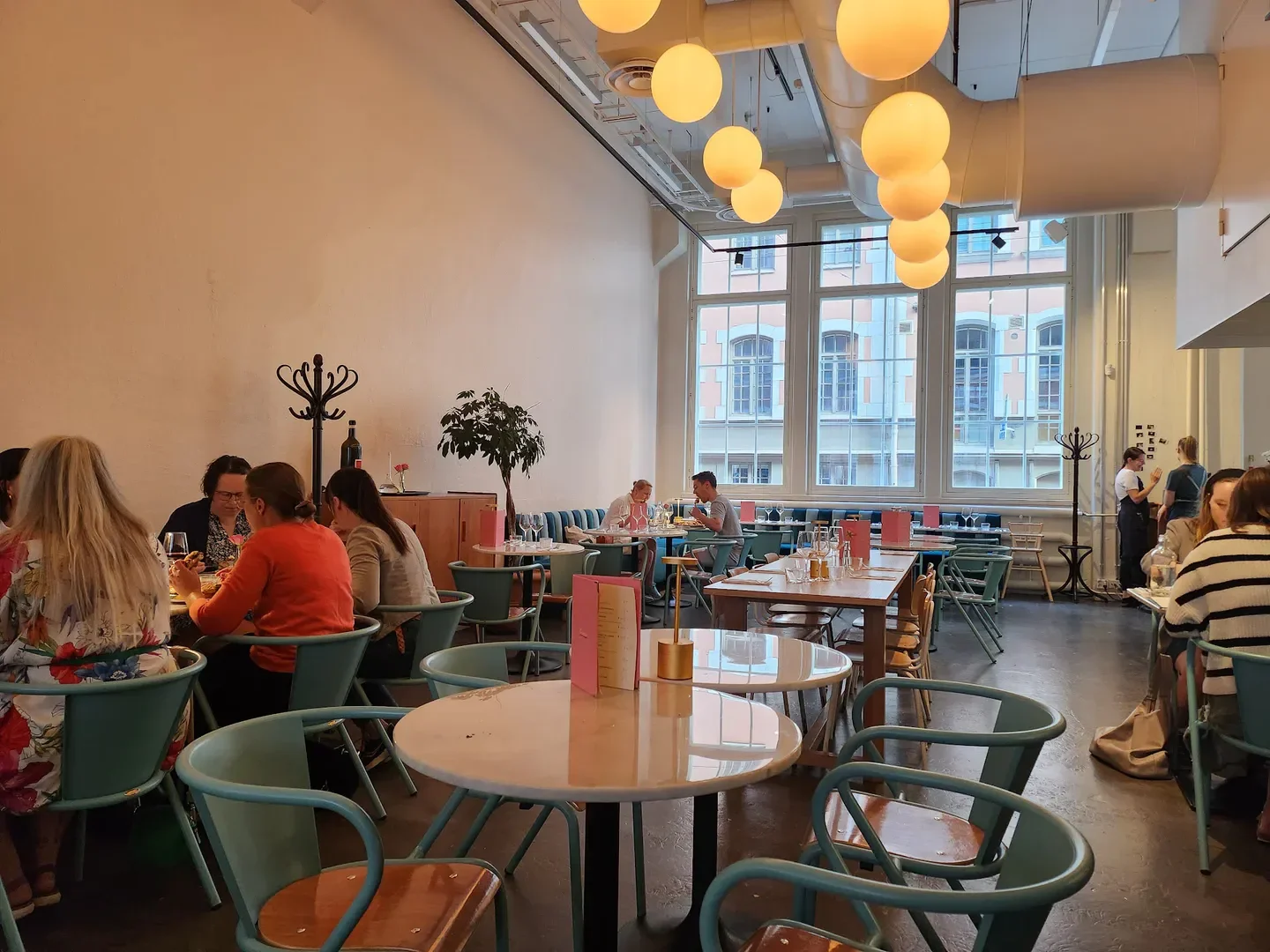 Interior dining at FORZA restaurant in Helsinki, featuring round tables and large windows.