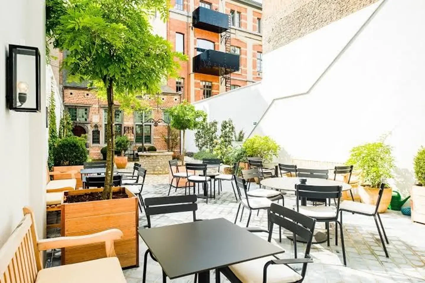 Outdoor dining at FRANQ restaurant in Antwerp with tables and green foliage.