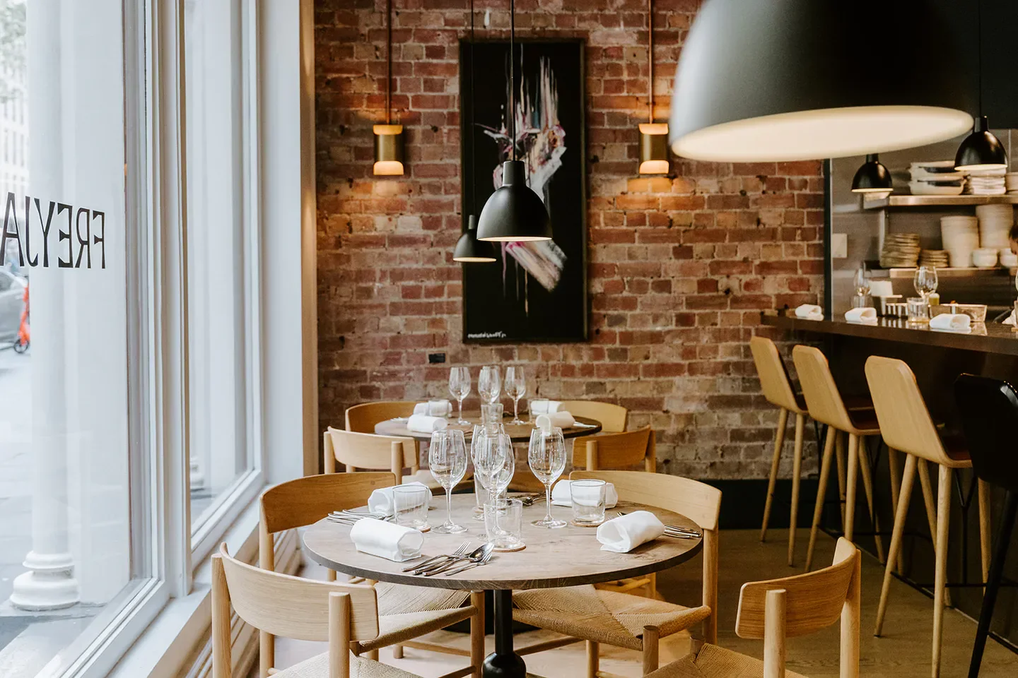 Interior of Freyja restaurant in Melbourne, featuring tables, chairs, and brick walls.