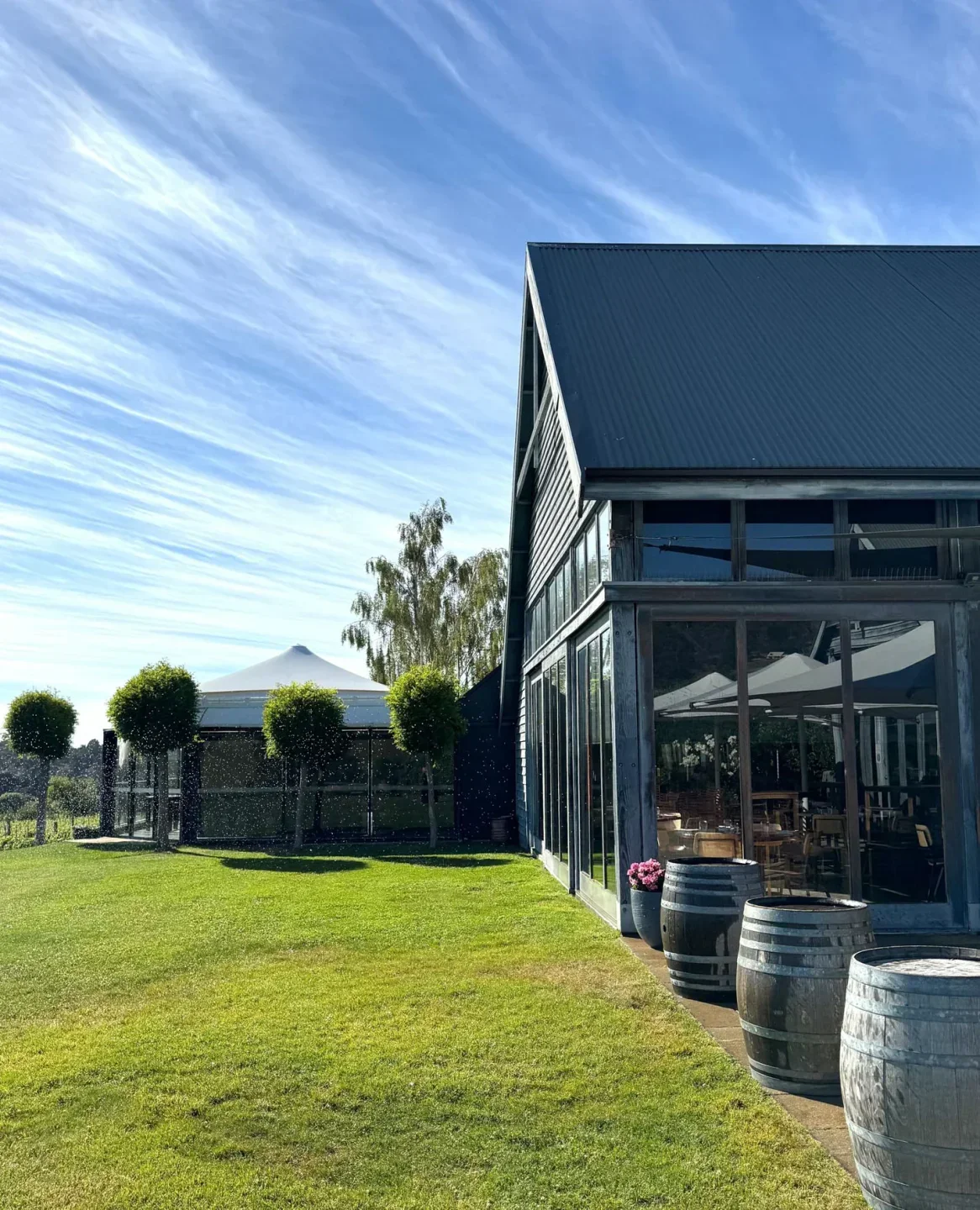 Exterior view of Frogmore Creek Restaurant & Cellar Door in Hobart with barrels and green lawn.