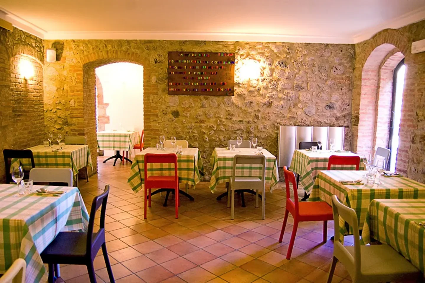 Cozy dining room at Futura Osteria in Tuscany, featuring stone walls and checkered tablecloths.