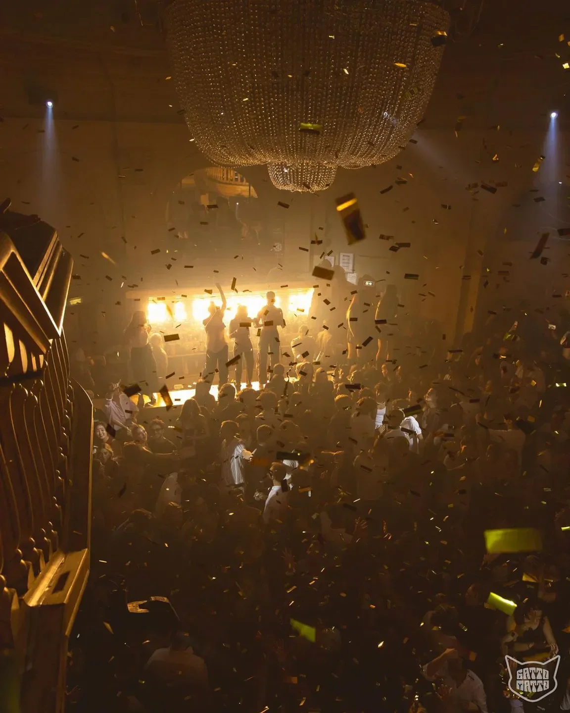 Energetic party scene at Gattopardo nightclub in Milan with confetti and chandelier.