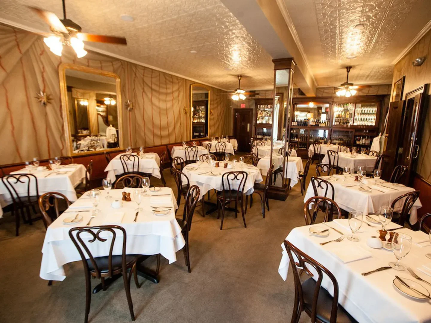 Elegant dining room interior at Gautreau's restaurant in New Orleans with tables set for service.