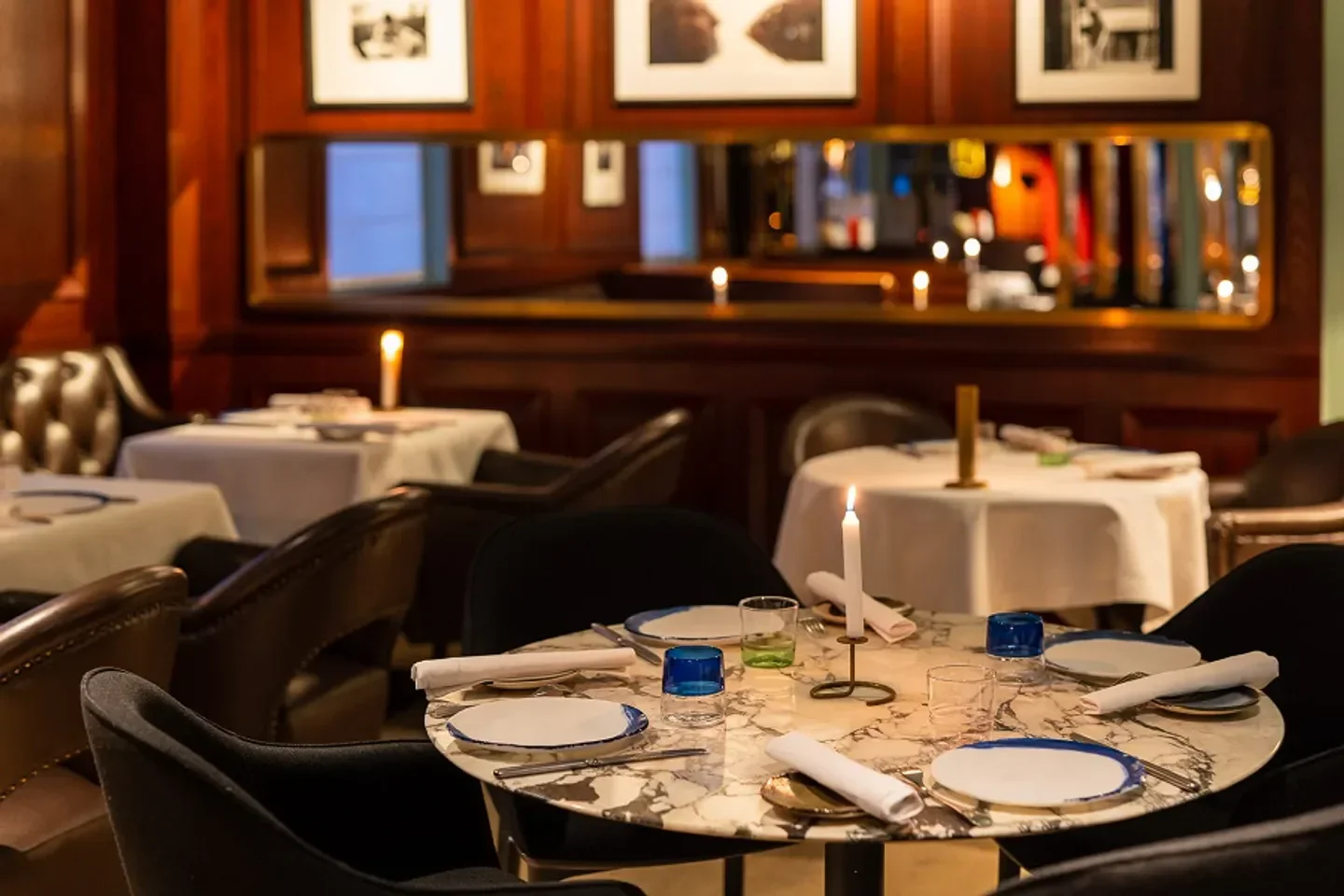 Cozy dining room with tables set at Gaya restaurant in Paris, featuring candle light.